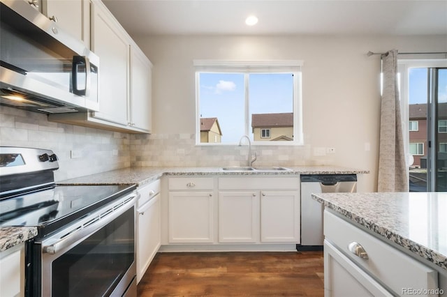 kitchen with appliances with stainless steel finishes, dark wood finished floors, a sink, white cabinets, and recessed lighting