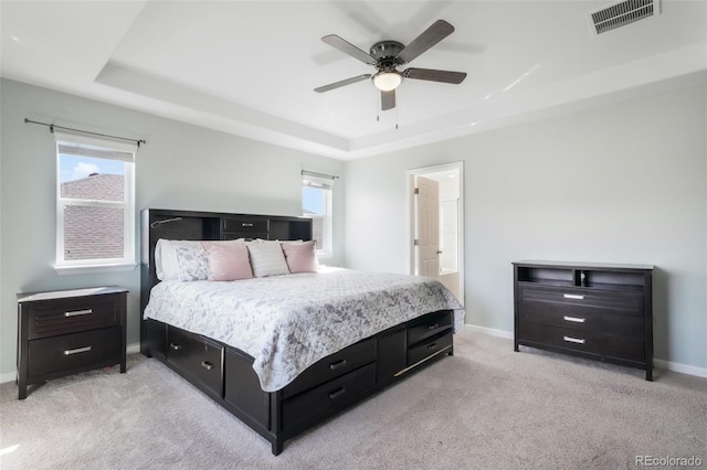 bedroom featuring a raised ceiling, baseboards, light colored carpet, and visible vents