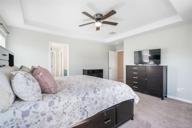 bedroom with baseboards, a tray ceiling, light colored carpet, and visible vents
