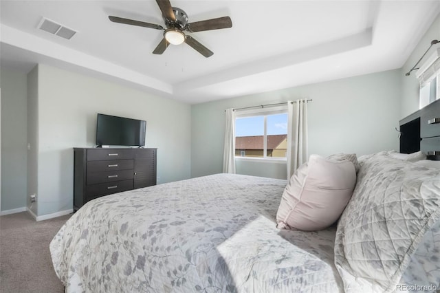 bedroom featuring multiple windows, a tray ceiling, carpet flooring, and visible vents