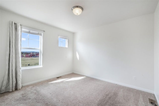 unfurnished room featuring baseboards, visible vents, and carpet