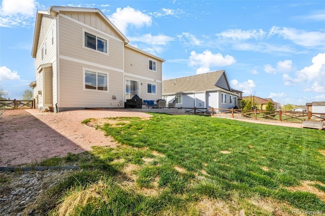 back of property featuring board and batten siding, a fenced backyard, a gate, a patio area, and a yard