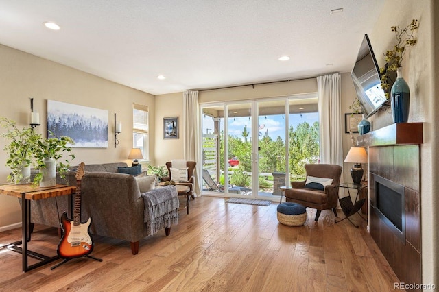 18067 E Anthem Dr, Parker, CO 80134 - living room featuring light wood-type flooring, a tiled fireplace, and recessed lighting