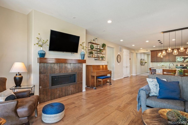 18067 E Anthem Dr, Parker, CO 80134 - living room with a tile fireplace, light wood finished floors, recessed lighting, and baseboards