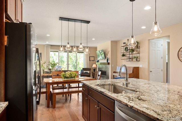 18067 E Anthem Dr, Parker, CO 80134 - kitchen with appliances with stainless steel finishes, a sink, light wood-style floors, light stone countertops, and recessed lighting