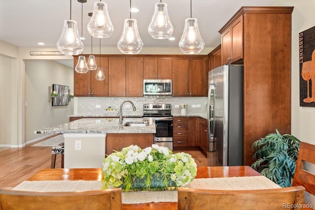 18067 E Anthem Dr, Parker, CO 80134 - kitchen featuring stainless steel appliances, a sink, backsplash, an island with sink, and light stone counters