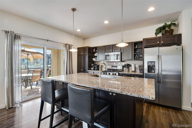 kitchen featuring sink, a breakfast bar area, appliances with stainless steel finishes, dark brown cabinets, and decorative light fixtures