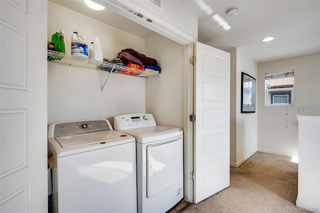 clothes washing area with light colored carpet and washer and clothes dryer