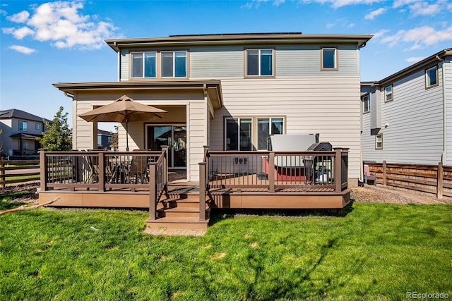 rear view of house featuring a deck and a lawn