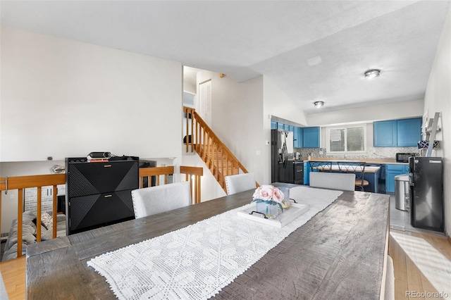 dining area with light hardwood / wood-style floors and vaulted ceiling