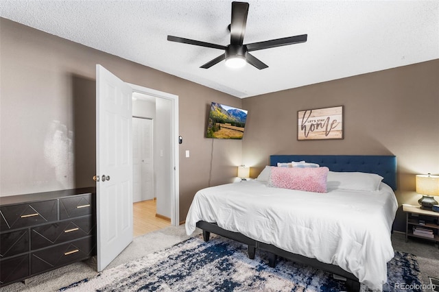 carpeted bedroom featuring ceiling fan and a textured ceiling