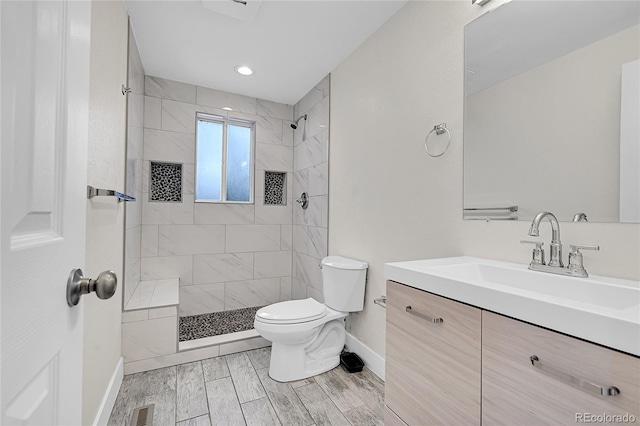 bathroom featuring toilet, vanity, and a tile shower