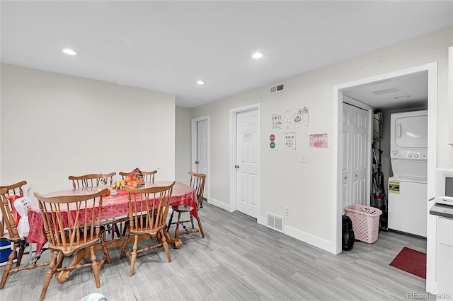 dining room featuring stacked washer / dryer and light hardwood / wood-style floors