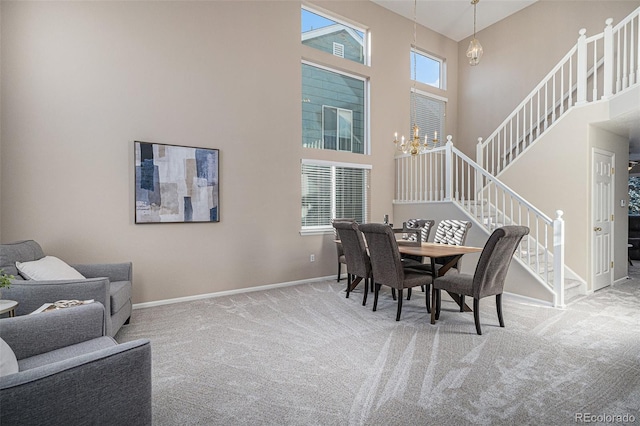 carpeted dining room with a wealth of natural light, a high ceiling, and a notable chandelier