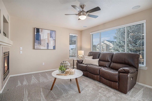 carpeted living room with ceiling fan, a textured ceiling, and a fireplace