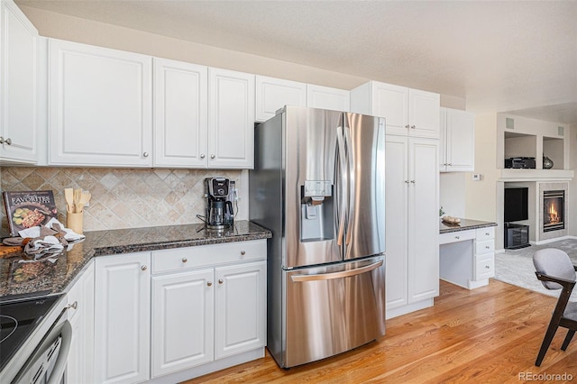 kitchen featuring stainless steel refrigerator with ice dispenser, white cabinetry, backsplash, and stove