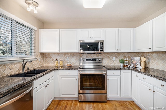 kitchen with stainless steel appliances, white cabinetry, sink, and light hardwood / wood-style flooring