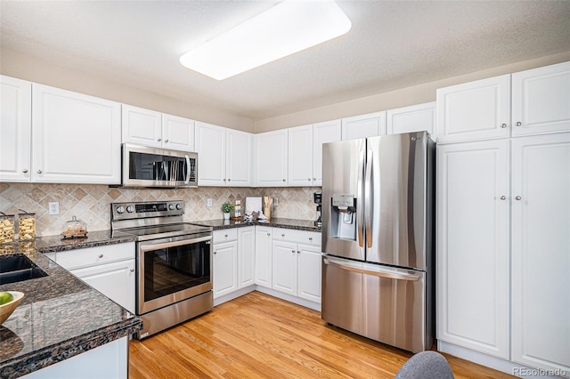 kitchen with backsplash, stainless steel appliances, light hardwood / wood-style floors, and white cabinets