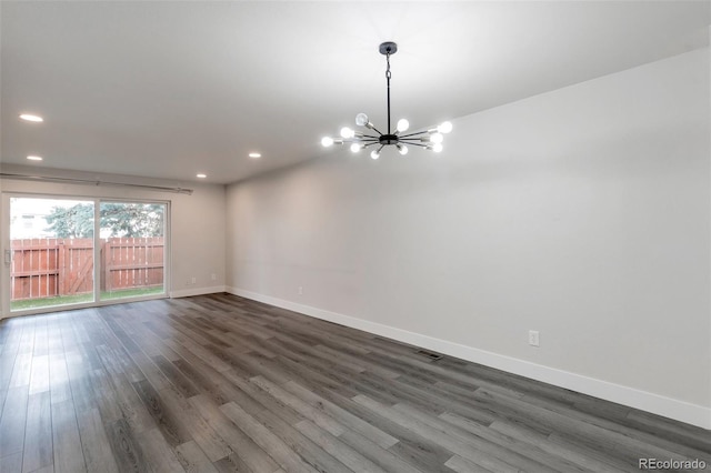 empty room with a chandelier and dark hardwood / wood-style floors