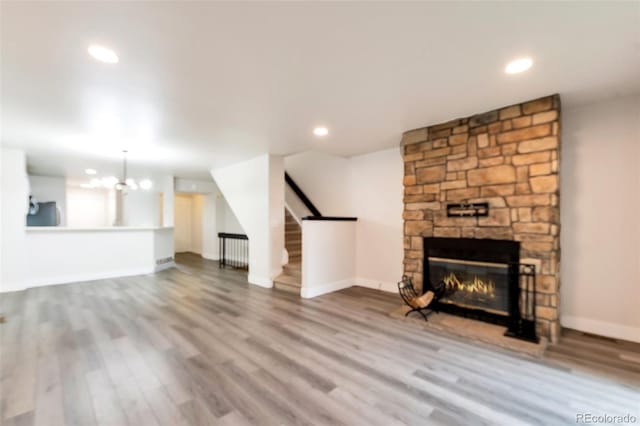 unfurnished living room with radiator heating unit, light wood-type flooring, a fireplace, and an inviting chandelier