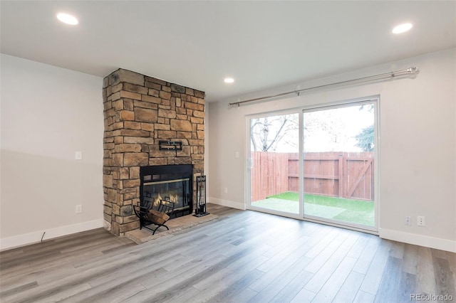 unfurnished living room featuring light wood-type flooring and a stone fireplace