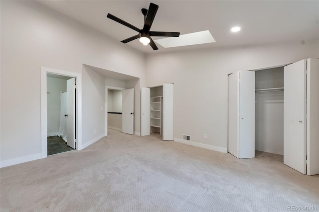 unfurnished bedroom with ensuite bath, two closets, ceiling fan, and a skylight