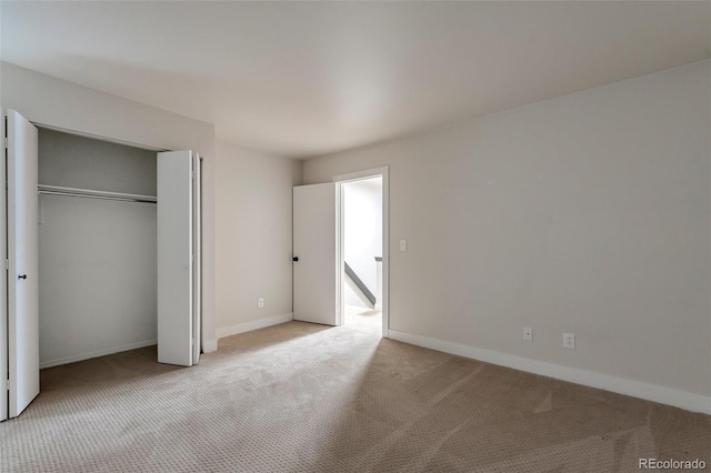 unfurnished bedroom featuring light carpet and a closet