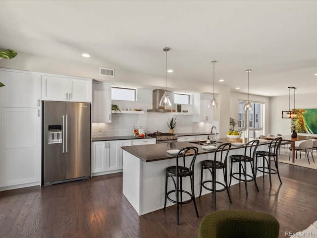 1819 Gaylord St, Denver, CO 80206 - kitchen with high quality appliances, dark countertops, a breakfast bar, decorative backsplash, and white cabinetry