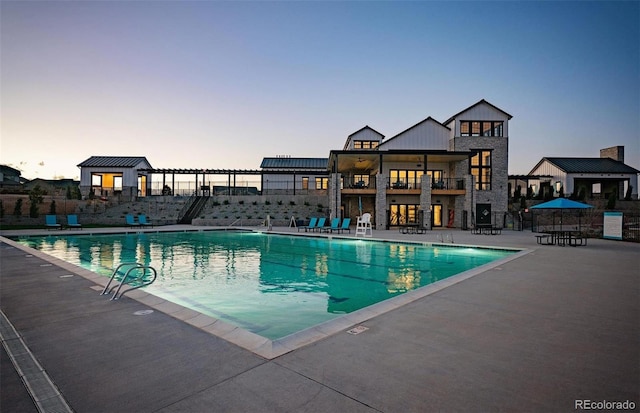 pool at dusk with a patio area