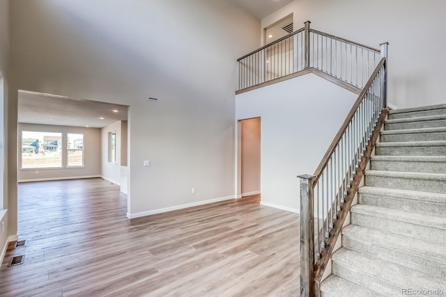 stairway featuring hardwood / wood-style floors and a towering ceiling