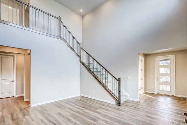 entryway featuring a towering ceiling and light wood-type flooring