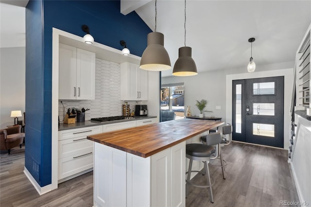 kitchen featuring wood counters, decorative light fixtures, stainless steel gas cooktop, and white cabinets