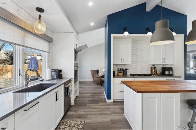 kitchen featuring pendant lighting, white cabinetry, sink, and butcher block countertops