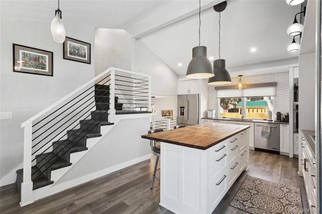 kitchen featuring wood counters, stainless steel appliances, a center island, and white cabinets