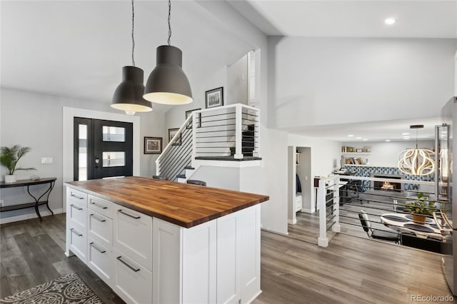 kitchen featuring dark wood-type flooring, hanging light fixtures, a center island, white cabinets, and wood counters