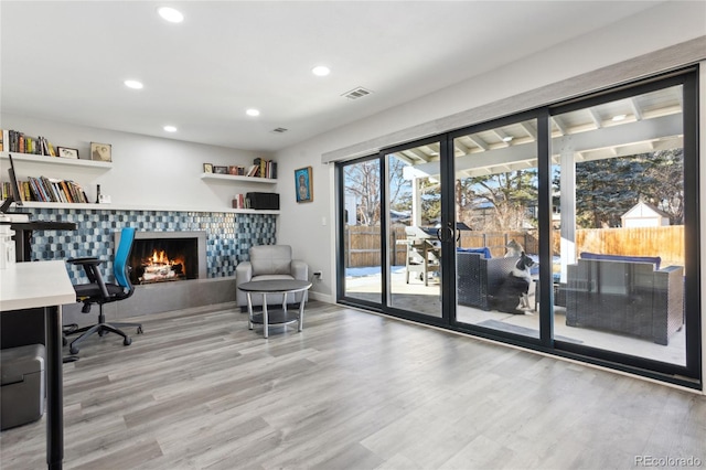 office area featuring a tiled fireplace and light wood-type flooring