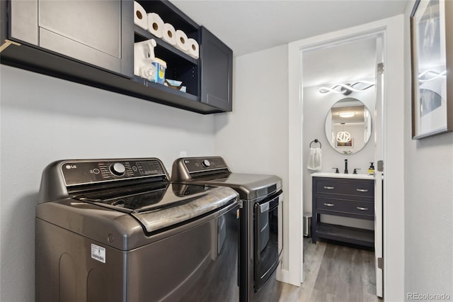 laundry area with washer and clothes dryer, light hardwood / wood-style floors, and cabinets