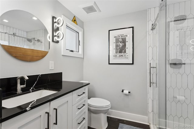 bathroom featuring vanity, toilet, hardwood / wood-style floors, and a tile shower