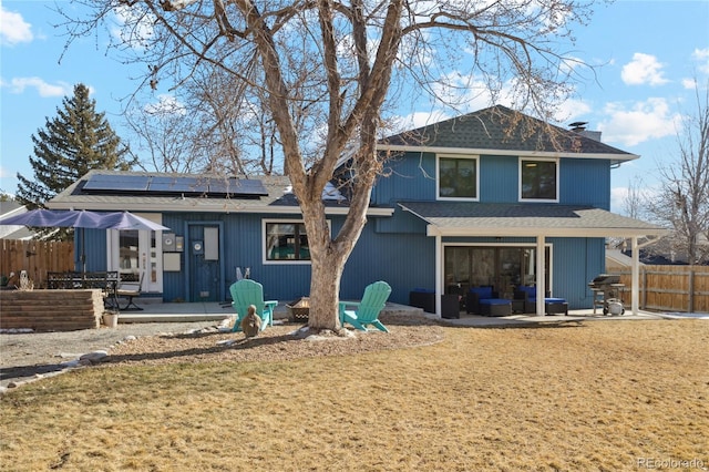 rear view of property with a lawn, a patio area, and solar panels