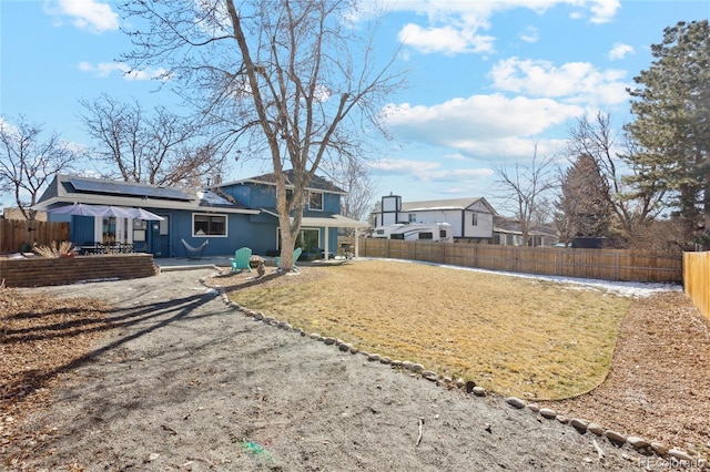 rear view of property featuring a patio and solar panels