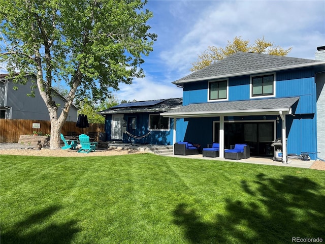 back of property with an outdoor living space, a lawn, a patio area, and solar panels