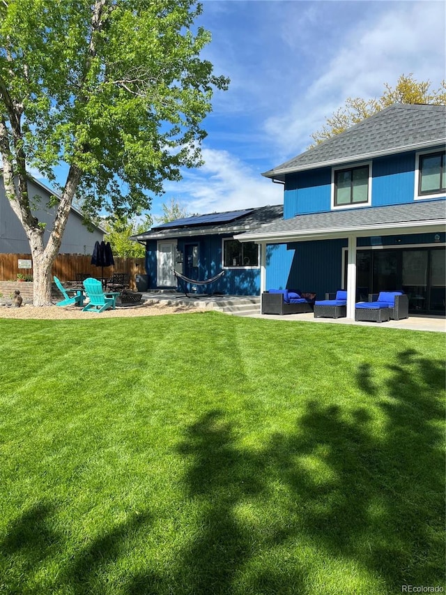 back of house with an outdoor living space, a patio area, and a lawn