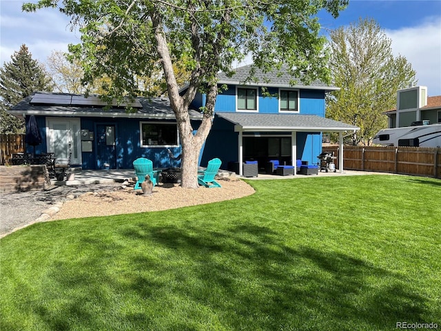 rear view of property featuring an outdoor living space, a patio, a lawn, and solar panels