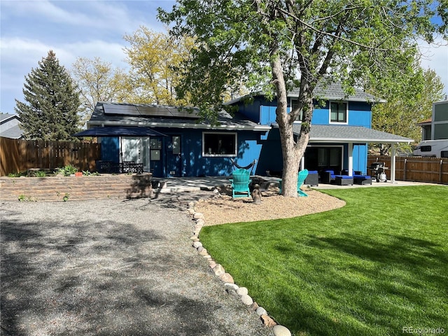 rear view of property featuring a yard, outdoor lounge area, a patio, and solar panels