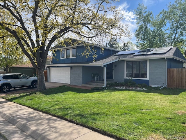 view of front facade with a garage, a front yard, and solar panels