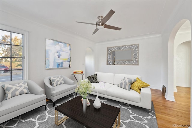 living room featuring hardwood / wood-style flooring, ceiling fan, and crown molding