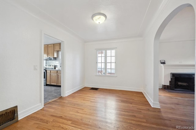 interior space featuring crown molding, a brick fireplace, and light hardwood / wood-style floors