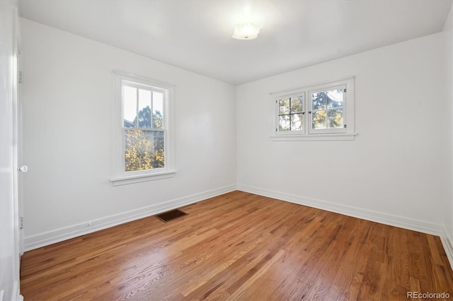 unfurnished room featuring a wealth of natural light and hardwood / wood-style floors