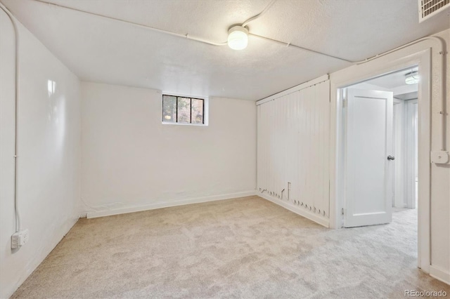 basement with a textured ceiling and light carpet