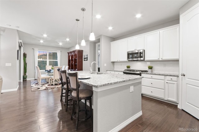 18922 W 84th Ave, Arvada, CO 80007 - kitchen featuring a kitchen island with sink, appliances with stainless steel finishes, dark wood finished floors, a sink, and white cabinetry